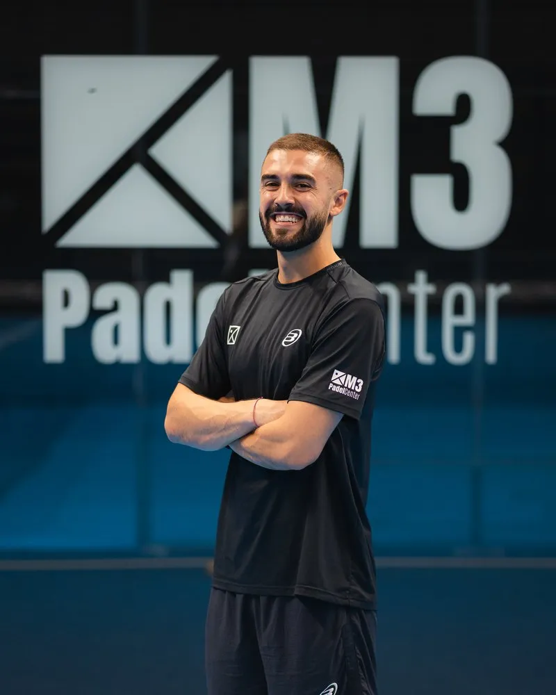 Coach Alex Hernández at The District, standing in front of the M3 Padel Center wall